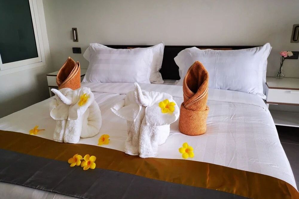 Komfortables Bett mit dekorativen Handtuchskulpturen und Blüten