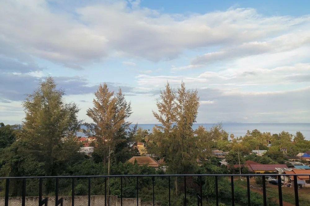 Eingeschränkter Meerblick vom Balkon mit Bäumen und Häusern im Vordergrund