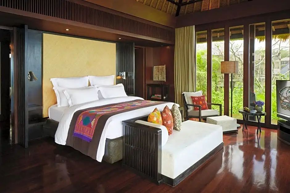 Eleganter Schlafbereich in der Bvlgari Villa mit großem Doppelbett und stilvollem balinesischen Interieur.