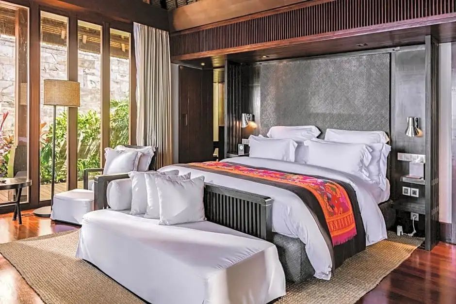 Geräumiges Doppelbett mit edler Bettwäsche und gemütlicher Sitzbank in einer exklusiven Villa.