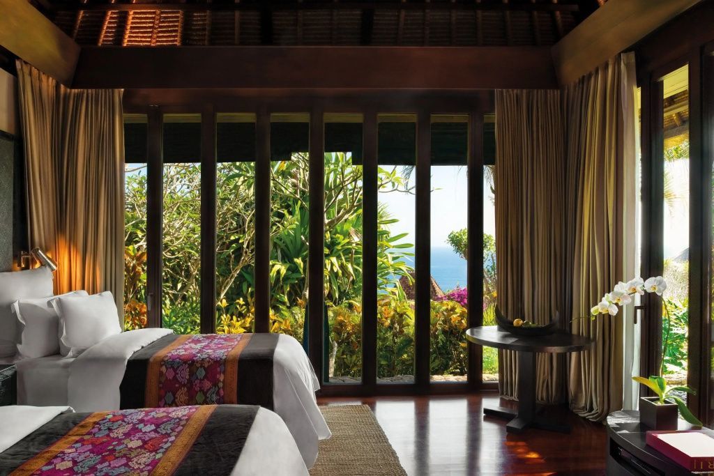 Blick aus der Villa durch große Fenster auf die tropische Natur und das Meer