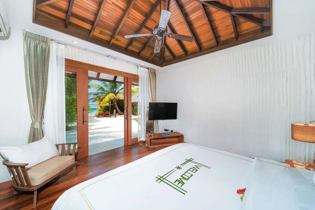 Gemütliches Schlafzimmer in einer Villa mit Blick auf den Strand und tropische Umgebung.