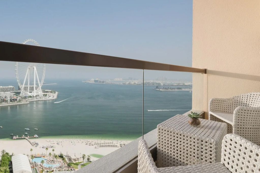 Balkon mit Aussicht auf das Meer und Ain Dubai, ausgestattet mit Sitzmöbeln.