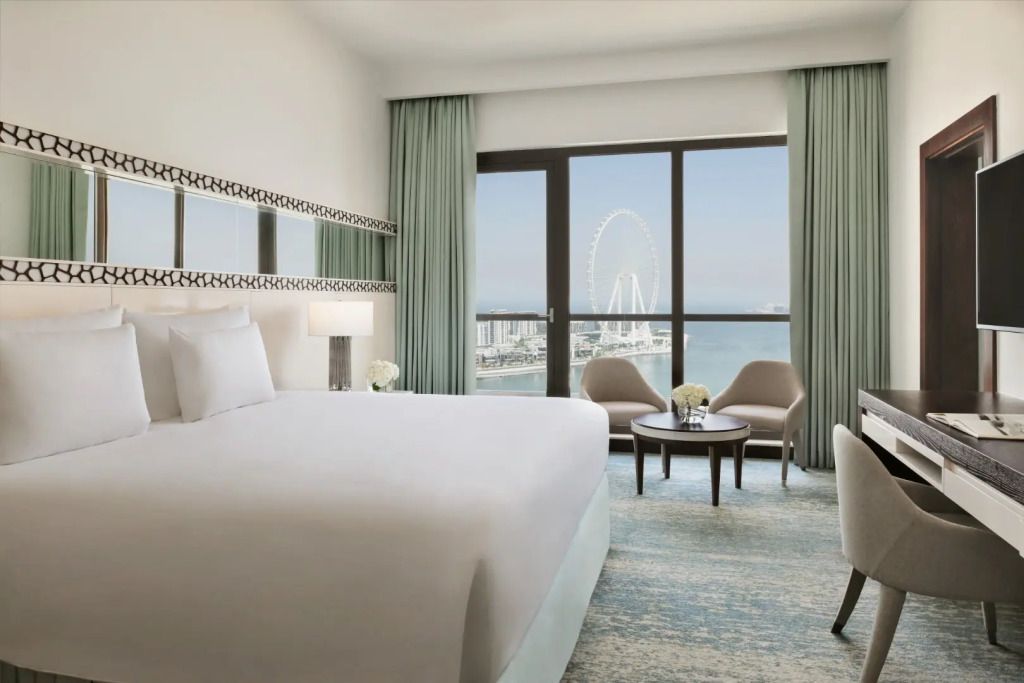 Helles Schlafzimmer mit Doppelbett und Blick auf das Riesenrad und das Meer.