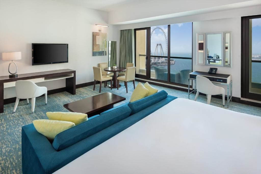 Zimmer mit großem Bett, Sitzbereich und Balkon mit Meerblick