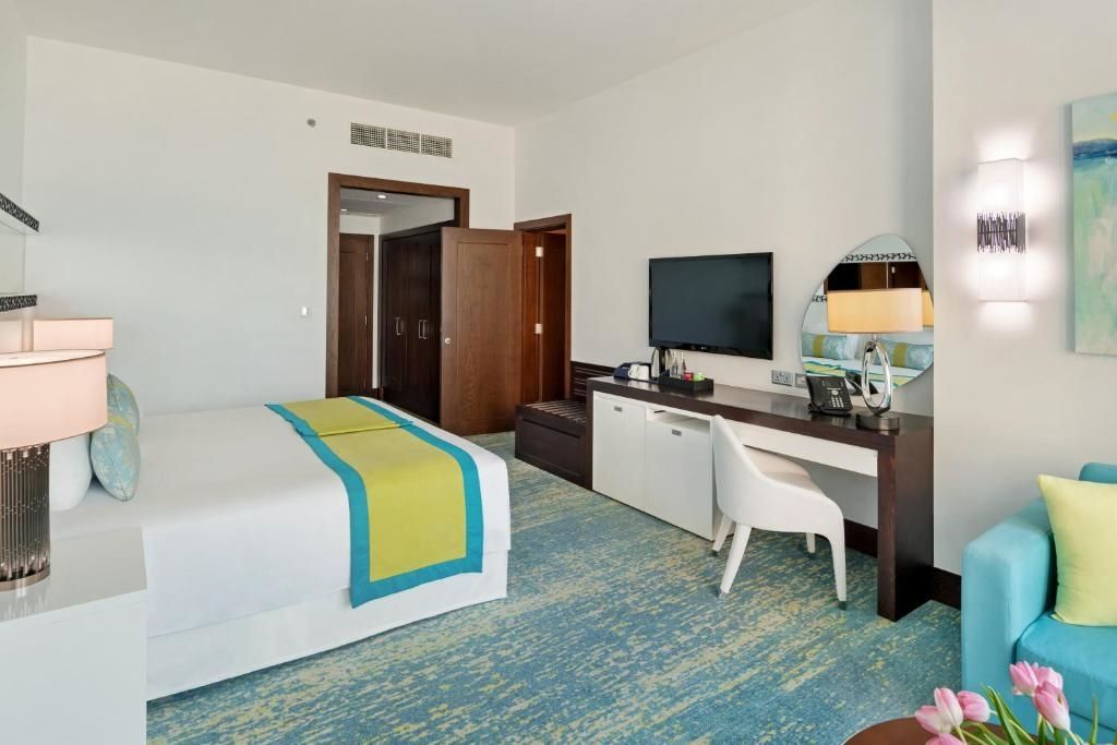 Hotelzimmer mit Schreibtisch, Fernseher und großem Bett