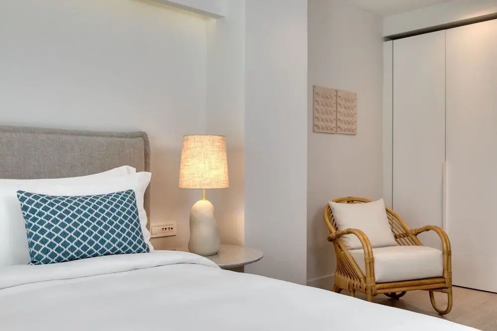 Gemütliche Sitzecke mit Rattan Sessel und stilvollem Doppelbett im Deluxe Zimmer.