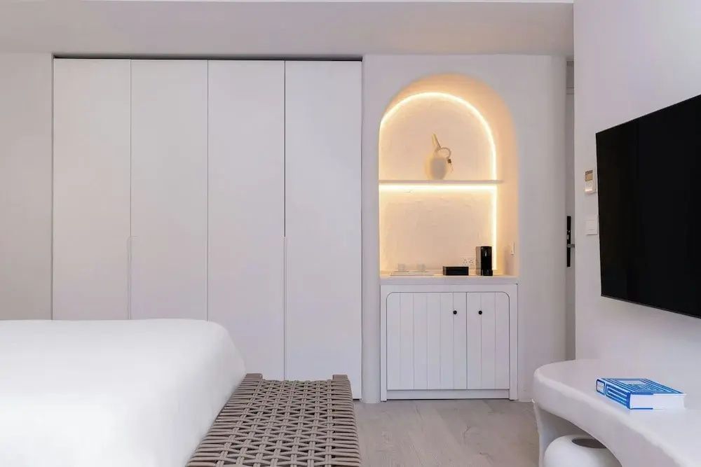 Eleganter Einbauschrank und beleuchtete Minibar im hellen Deluxe Doppelzimmer.