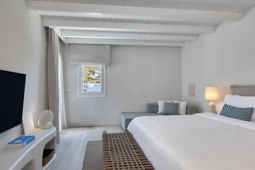 Hell gestaltetes Grand Doppelzimmer mit Holzbalkendecke und gemütlicher Sitzecke im Patmos Aktis Resort.