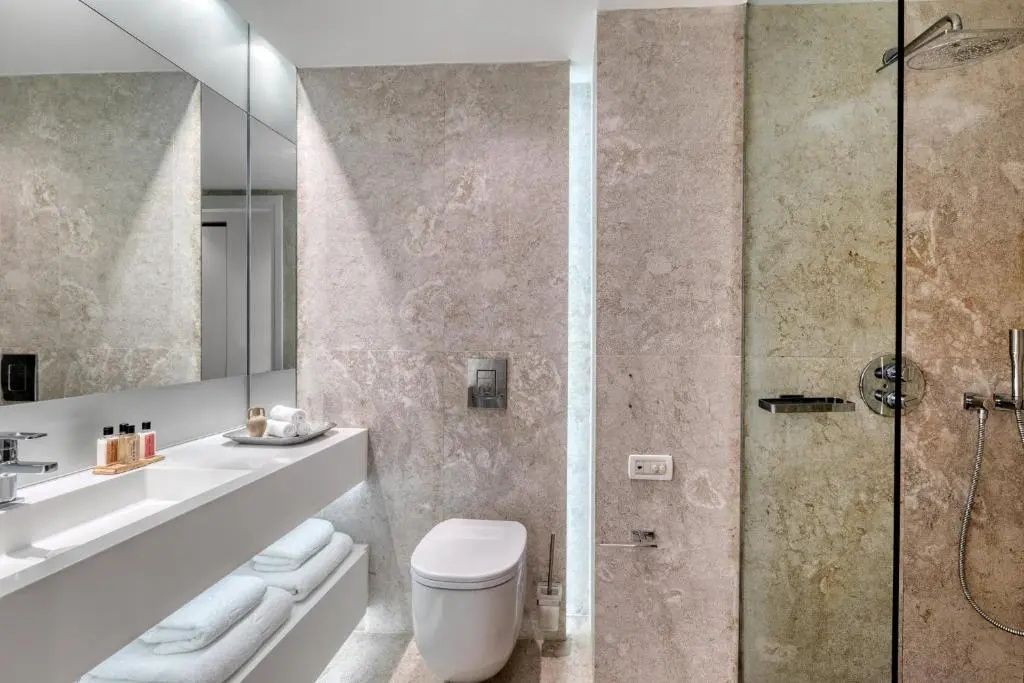 Modernes Badezimmer aus Naturstein mit Waschtisch und Dusche im Patmos Aktis Resort.