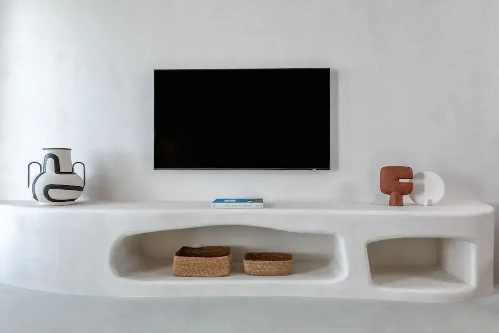 Wandmontierter Flachbildfernseher über weißem Nischenregal im kykladischen Stil im Patmos Aktis Resort.