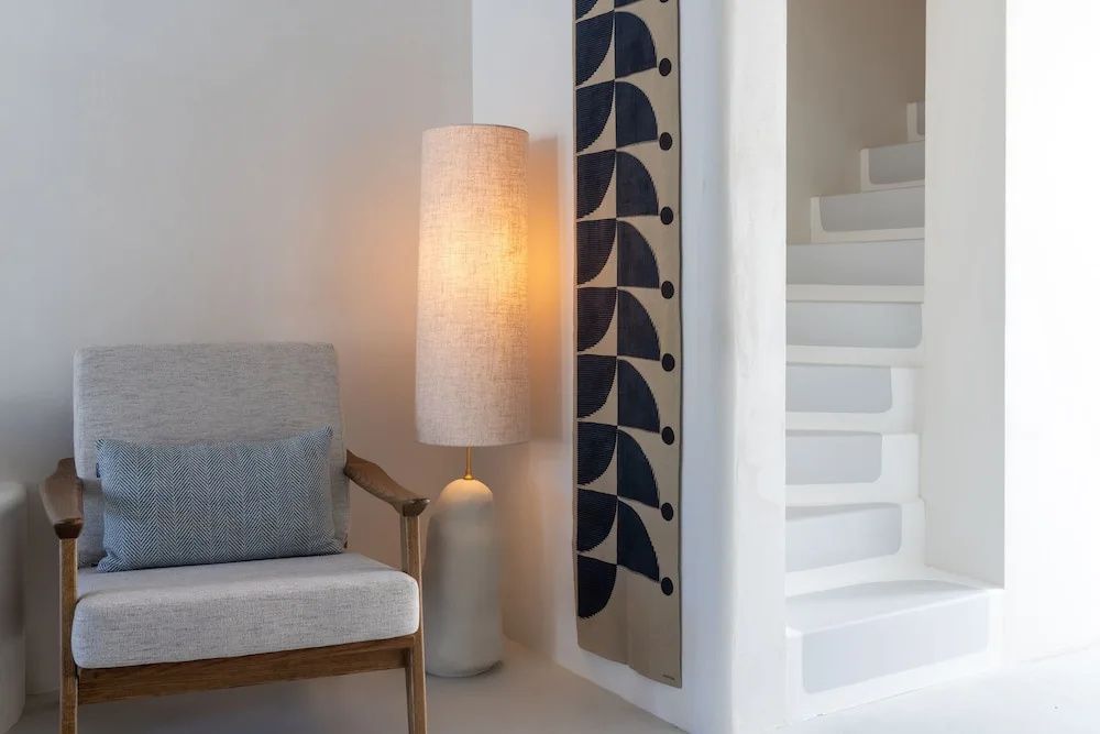 Eleganter Sessel neben einer hohen Stehlampe und kykladischer Architektur im Patmos Aktis.