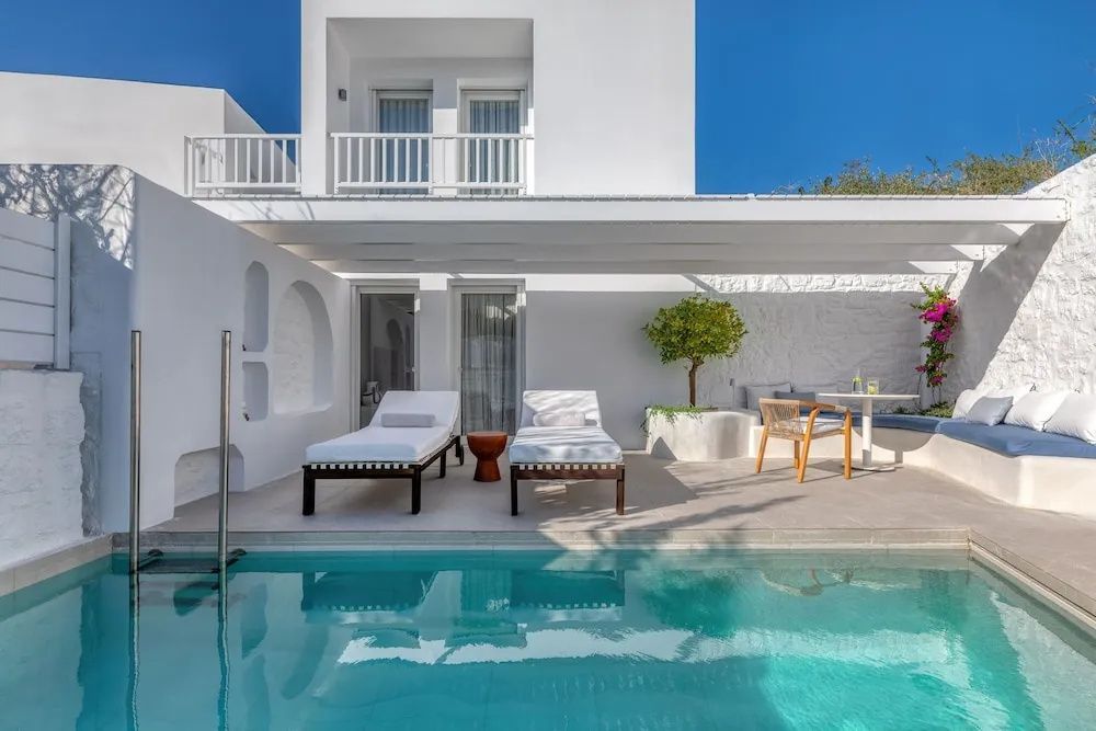 Private Terrasse mit Swimmingpool, Sonnenliegen und strahlend weißer Architektur am Meer.
