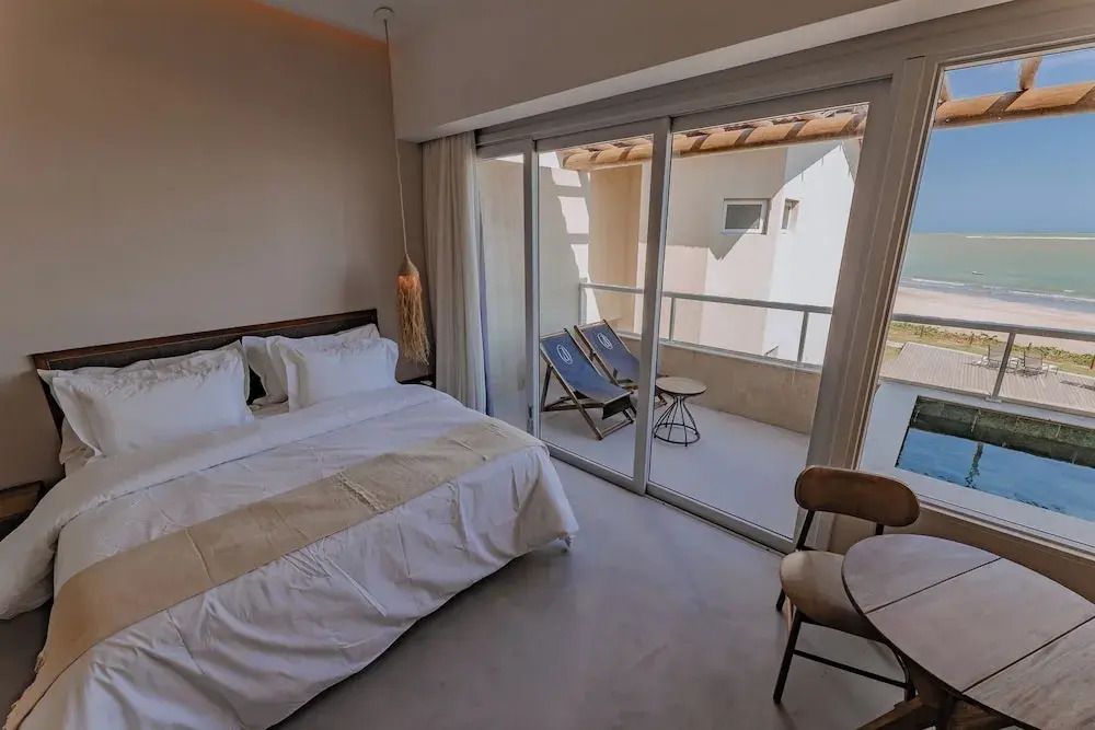 Helles Zimmer mit Doppelbett und Zugang zum Balkon mit Liegestühlen