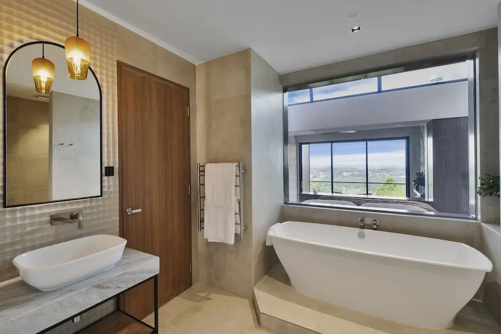 Badezimmer mit freistehender Badewanne und Fenster mit Naturblick