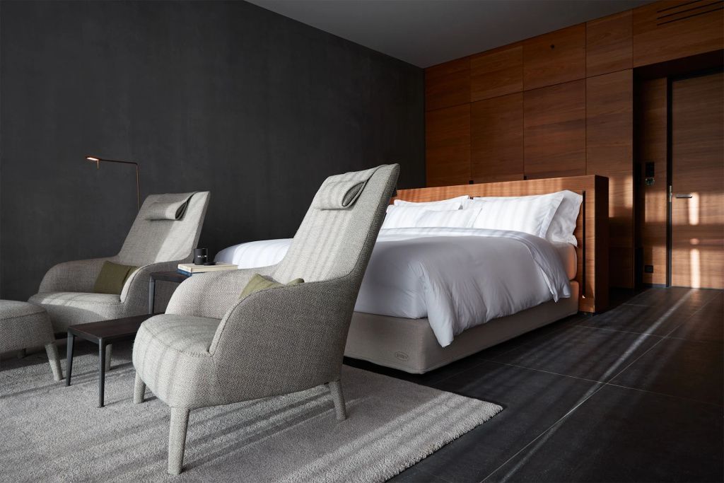 Doppelbett in der Junior-Suite mit edlen Holz- und Steinakzenten sowie gemütlichen Sesseln.