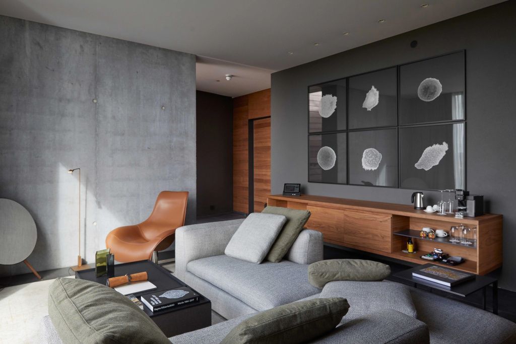Stilvoller Wohnbereich der Lagoon Suite mit moderner Einrichtung, Ledersessel und Sichtbeton.