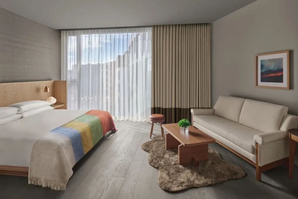 Heller Wohnbereich im Familienzimmer mit gemütlichem Sofa, Holztisch und großer Fensterfront.