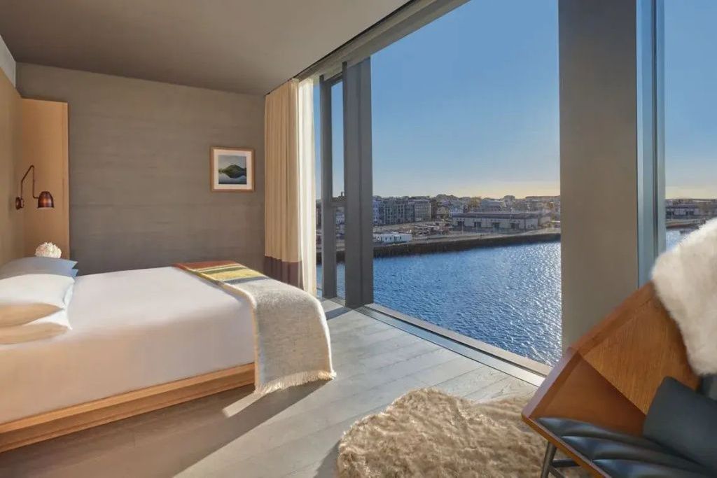 Schlafzimmer der Corner Penthouse Suite mit Doppelbett und bodentiefem Fenster zum Hafen.