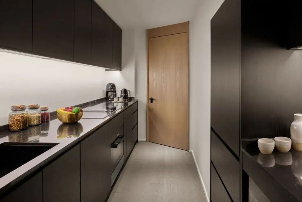 Moderne Küchenzeile in der Suite mit hochwertigen Geräten und dunkler Front.