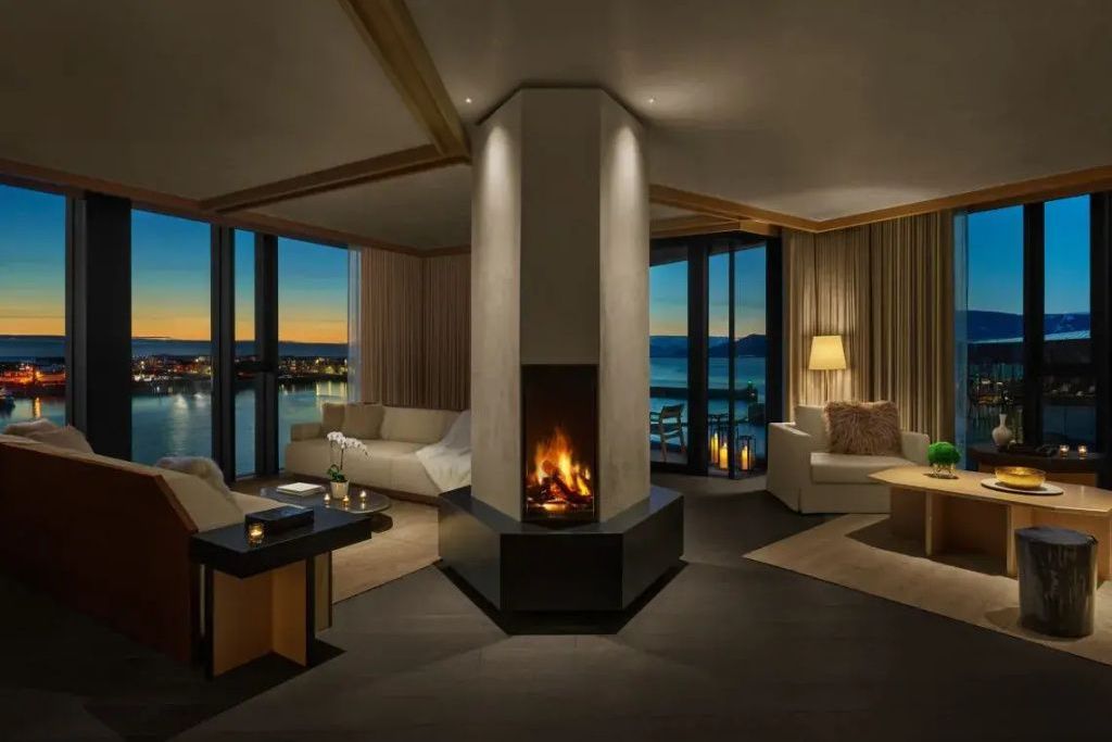 Luxuriöses Wohnzimmer im Penthouse mit modernem Kamin und Blick auf die Küste bei Nacht.