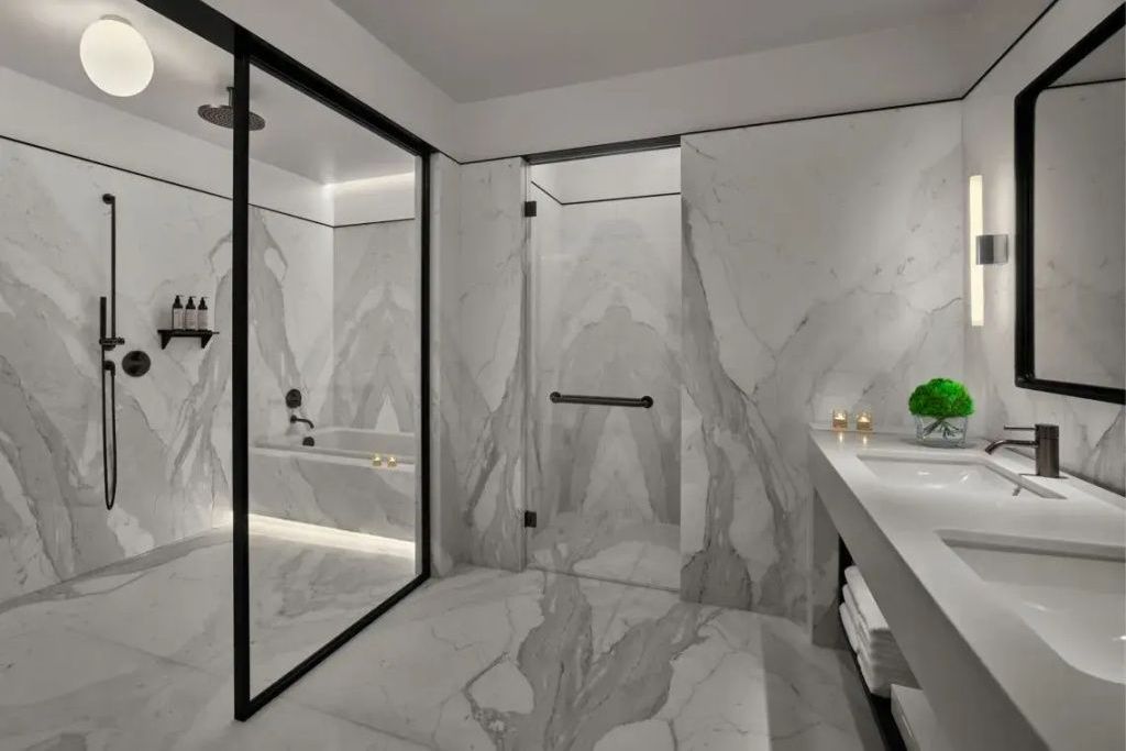 Luxuriöses Badezimmer aus weißem Marmor mit verglaster Dusche und Badewanne.