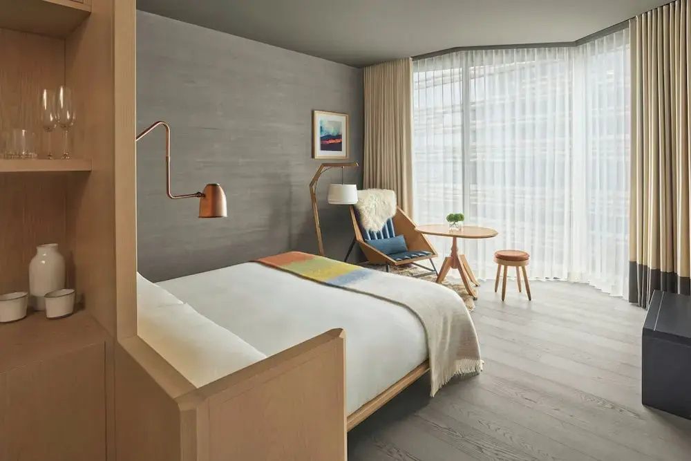Helles Doppelzimmer mit Holzfußboden, stilvoller Sitzecke und großem Fenster zum Innenhof.