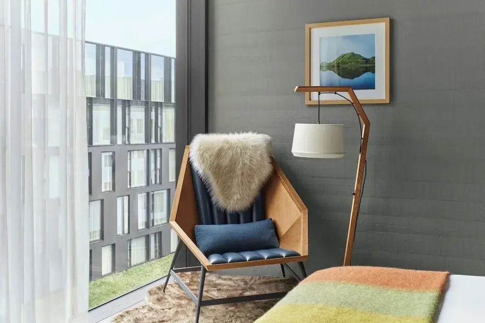 Gemütlicher Sessel mit Lammfell und Stehlampe am Fenster mit Blick auf die Innenhoffassade.