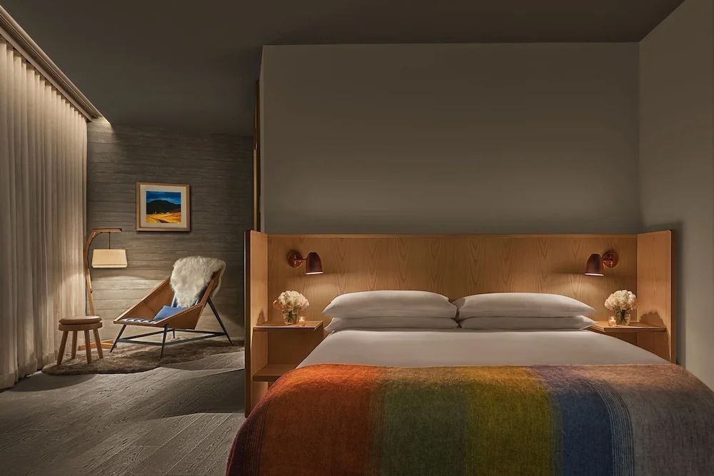 Komfortables Doppelbett mit bunter Decke und edlem Holzkopfteil im Zimmer.