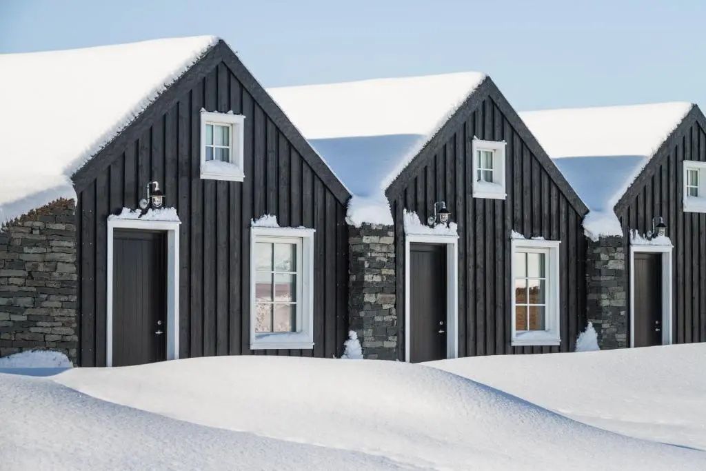 Traditionelle schwarze Holzhäuser des Torfhús Retreat im tiefen Schnee.