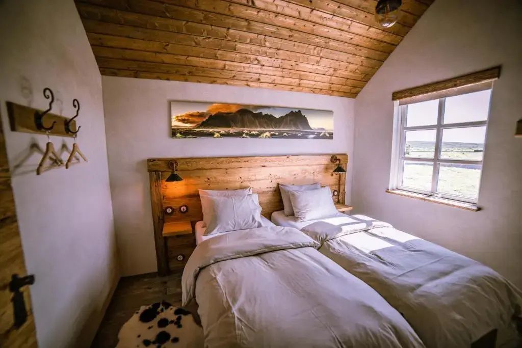 Gemütliches Deluxe Doppelzimmer mit rustikaler Holzdecke und Treibholz Kopfteil.