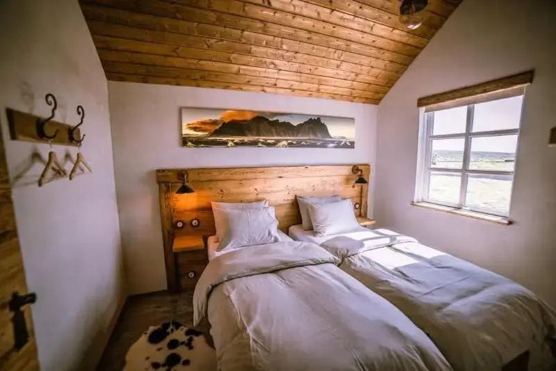 Gemütliches Schlafzimmer mit zwei Betten und Holzvertäfelung im Torfhús Retreat.