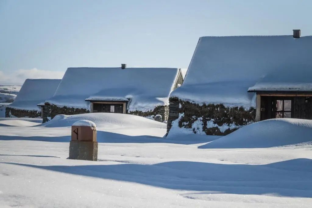 Verschneite Torfhäuser des Torfhús Retreats in tiefer Winterlandschaft