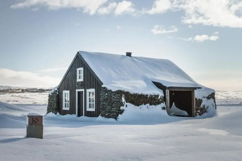 Isländische Suite im Torfhús Retreat mit Schneedecke unter blauem Himmel