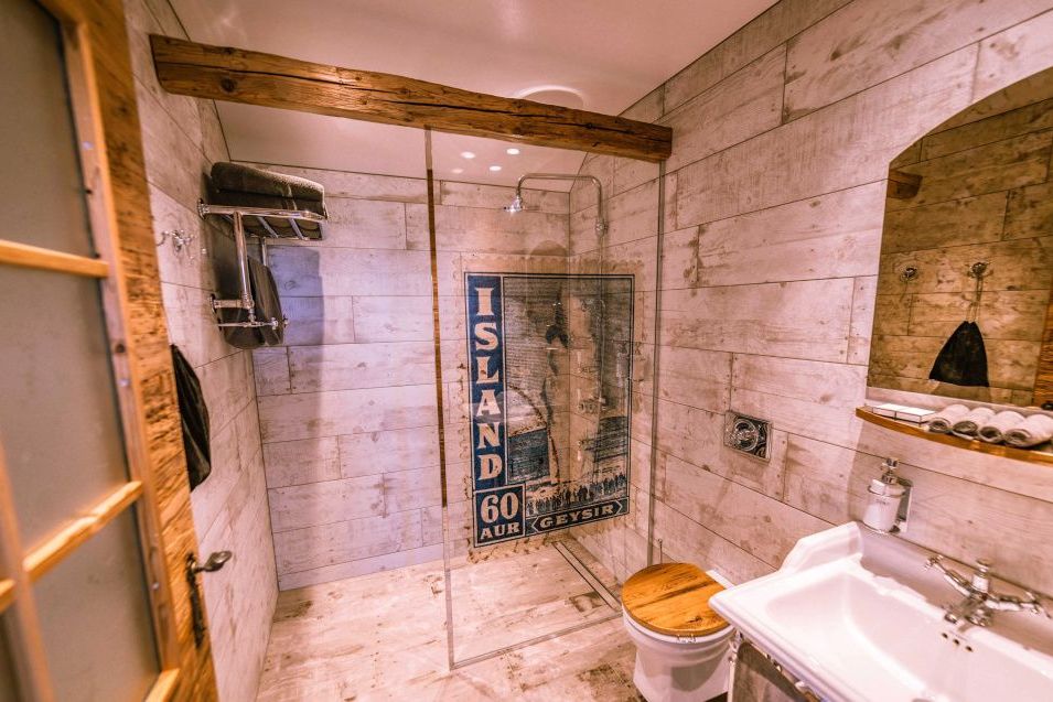 Badezimmer mit geräumiger Glasdusche, historischen Wanddetails und stilvoller Holzausstattung.