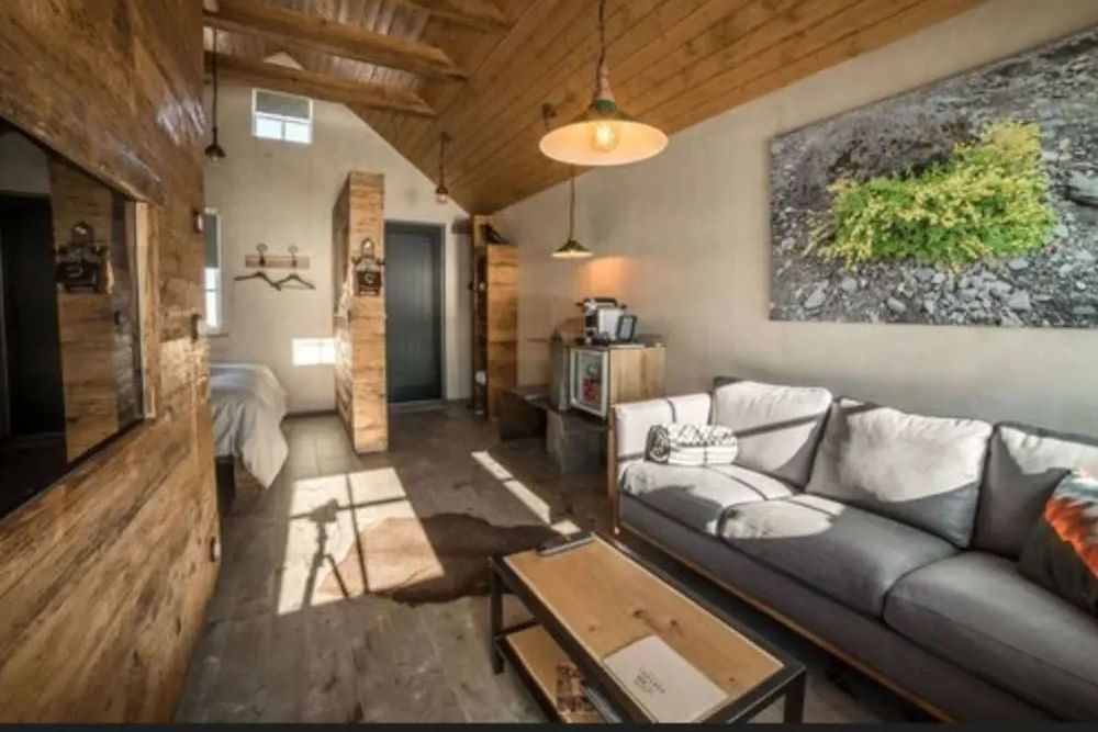 Gemütlicher Wohnbereich der Suite im Torfhús Retreat mit edlem Sofa und warmem Holzdesign.