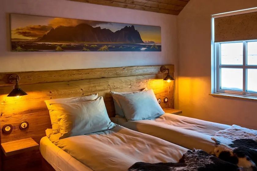 Bett in der Suite mit warmem Licht und eindrucksvollem Landschaftsbild über dem Kopfteil.