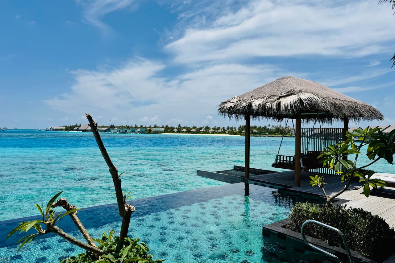 Privatpool einer Villa im Hilton Maldives Amingiri mit Schaukel unter dem Strohdach, dahinter die Lagune