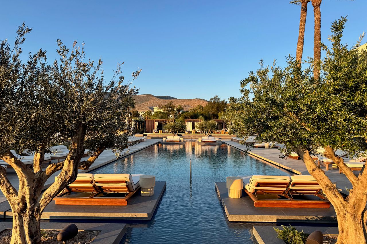 Pool des One&Only Aesthesis in Glyfada mit Liegen zwischen Olivenbäumen im Abendlicht