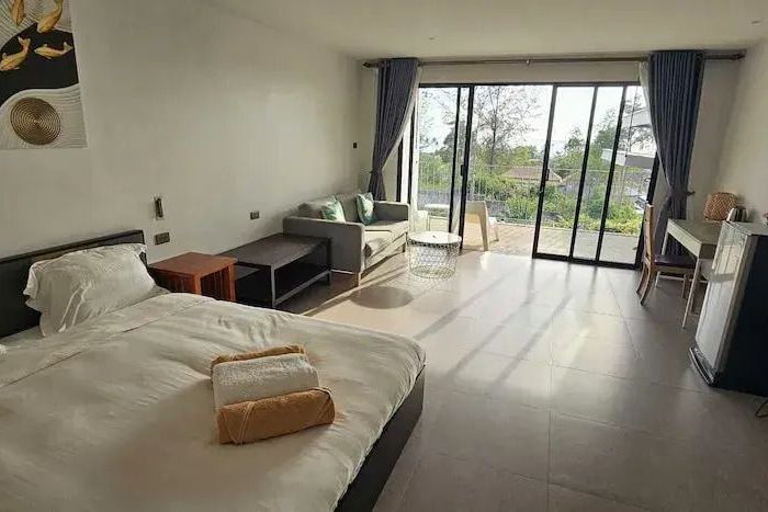 Helles Zimmer mit Doppelbett, Sofa und Balkonblick
