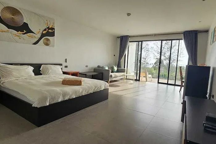 Großes Zimmer mit Bett und Sitzbereich vor Balkon