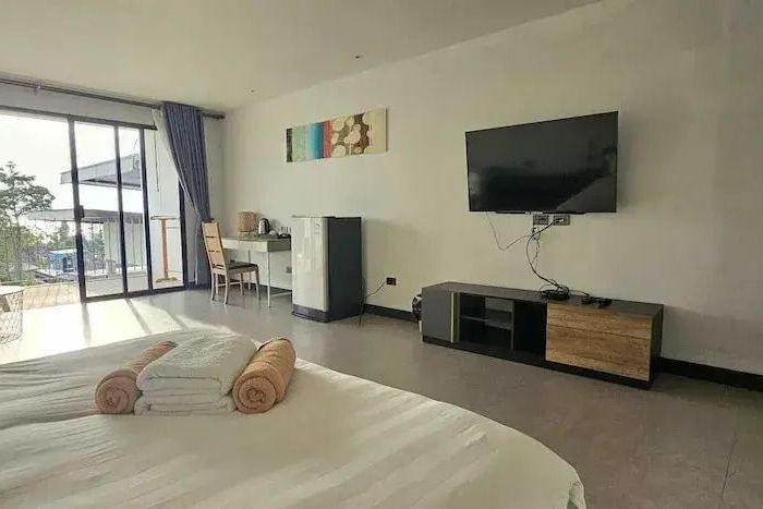 Zimmer mit Bett, Fernseher und Balkonzugang