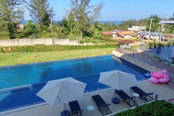 Poolbereich mit Liegen und Blick auf das Meer und den Garten
