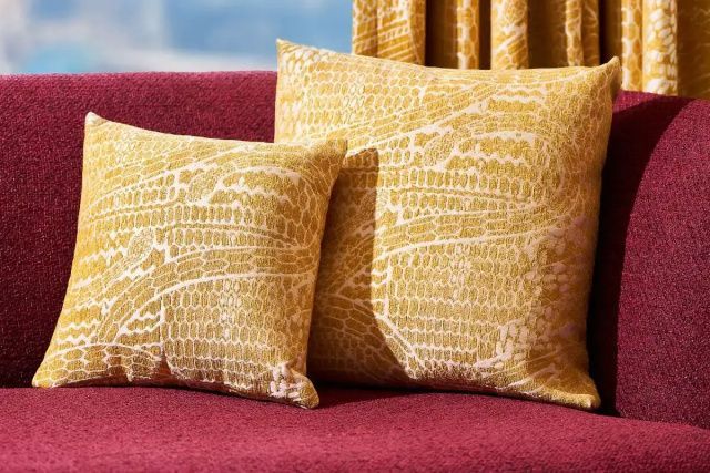 Gelbe Kissen mit Schlangenmuster auf einem roten Sofa in der Serpenti Villa.