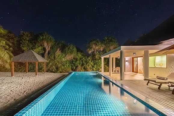 Nachtaufnahme eines Infinity-Pools mit Sternenhimmel