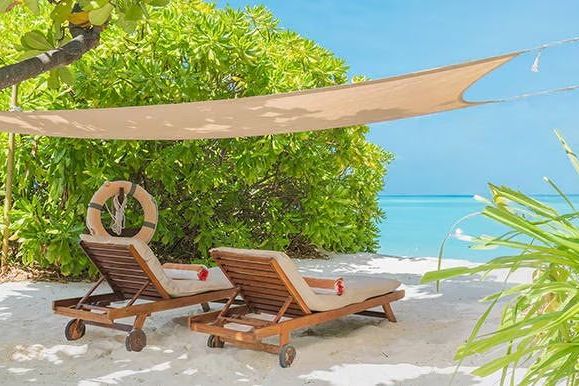 Strand mit Liegestühlen und Sonnenschutz vor türkisfarbenem Meer