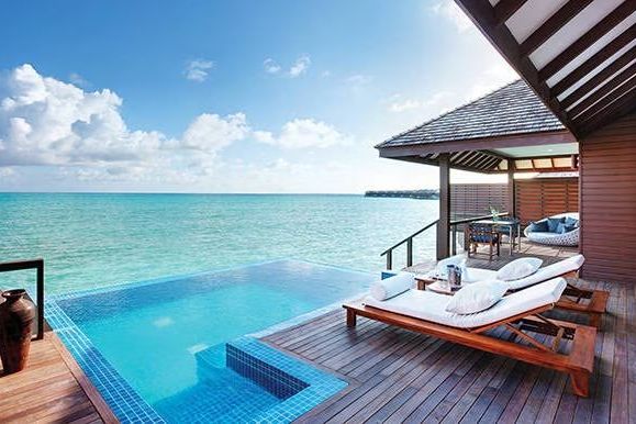 Privater Pool auf einer Holzterrasse mit Blick auf das Meer bei klarem Himmel