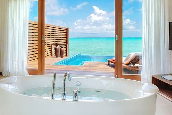 Badezimmer mit freistehender Badewanne und Aussicht auf das türkisfarbene Meer