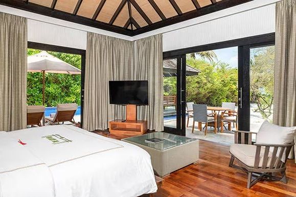 Elegantes Schlafzimmer mit Poolblick und Holzfußboden im luxuriösen Resort
