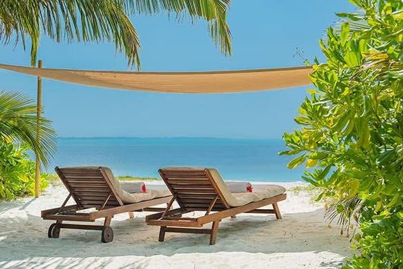 Sonnenliegen am weißen Sandstrand mit Meerblick im Luxusresort